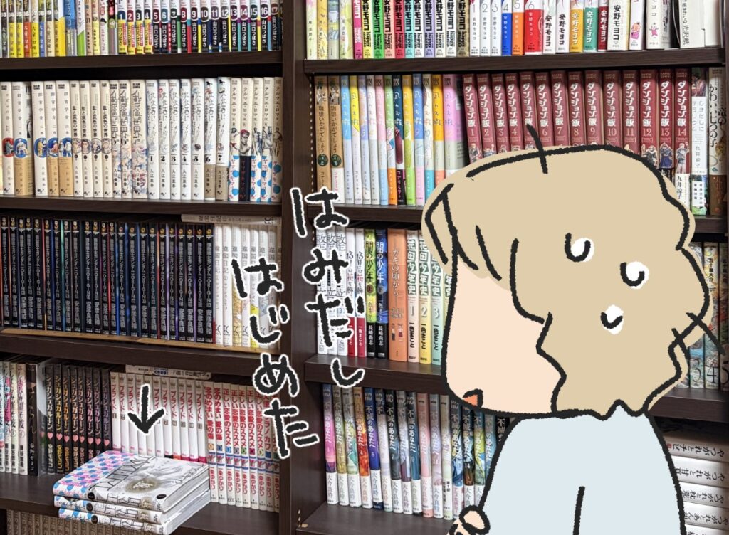 漫画でいっぱいの本棚。棚に入りきらない本が手前に積まれ「はみだしはじめた」と見つめる私